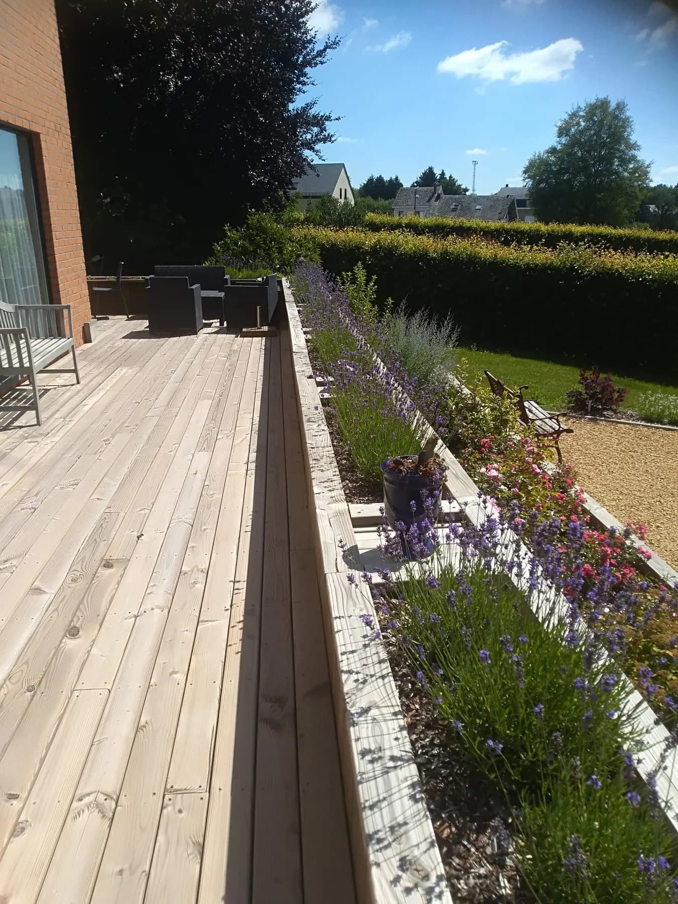 Terrasse en bois bordée d’un massif de lavandes